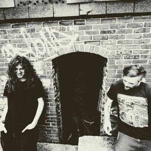 KIN duo portrait in black and white, standing at a brick archway