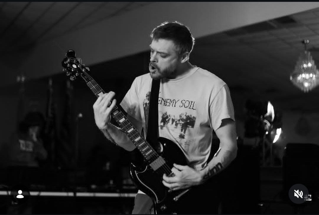 Black and white live closeup of the guitarist screaming into the microphone